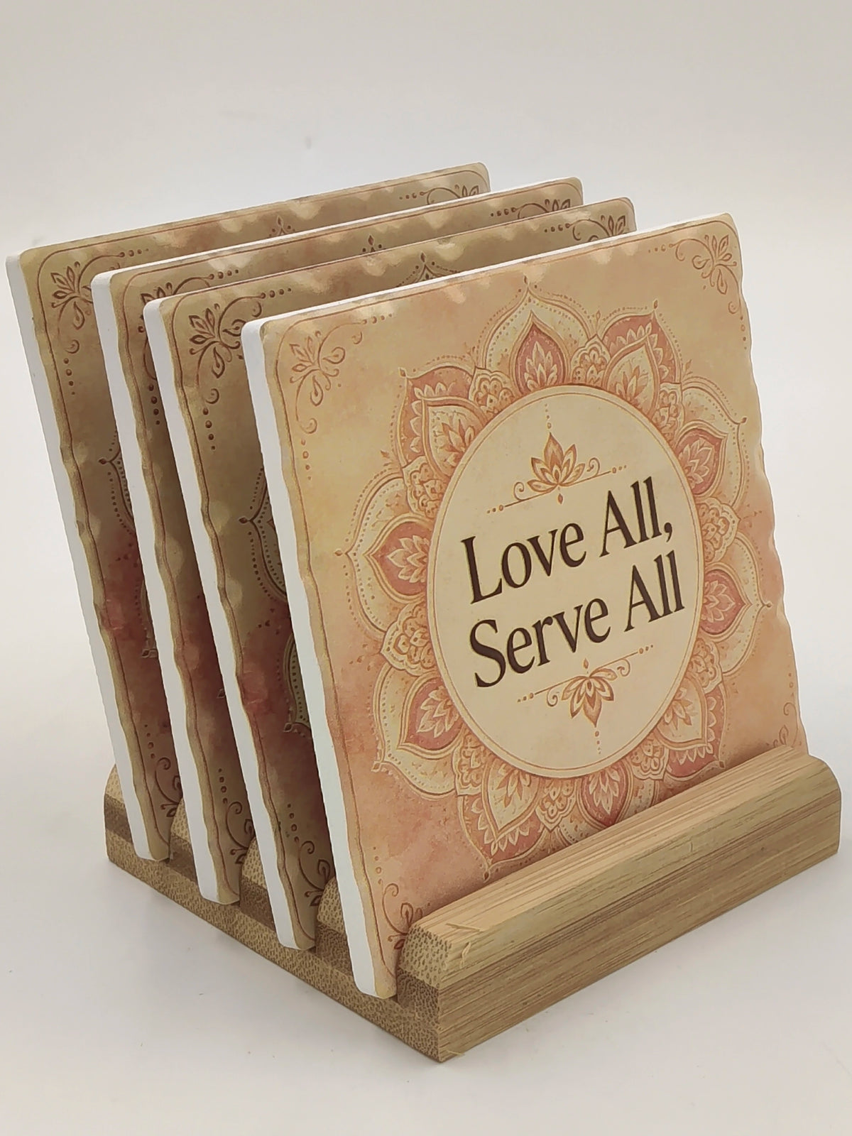Set of four ceramic coasters with 'Love All, Serve All' text and mandala design