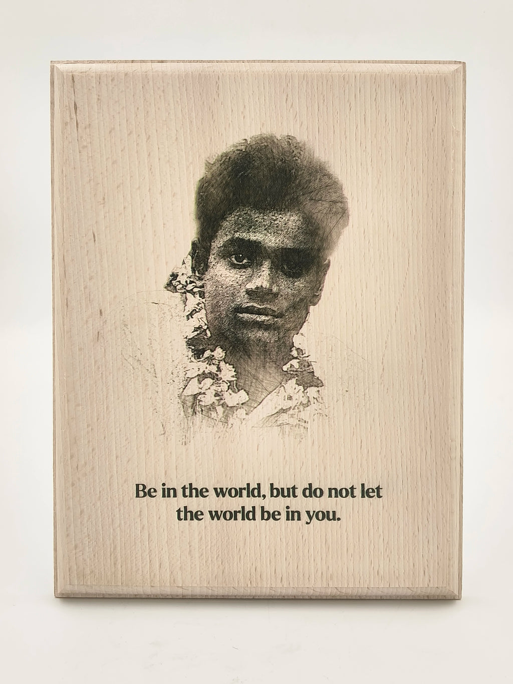 Wooden plaque with a portrait and the quote 'Be in the world, but do not let the world be in you'