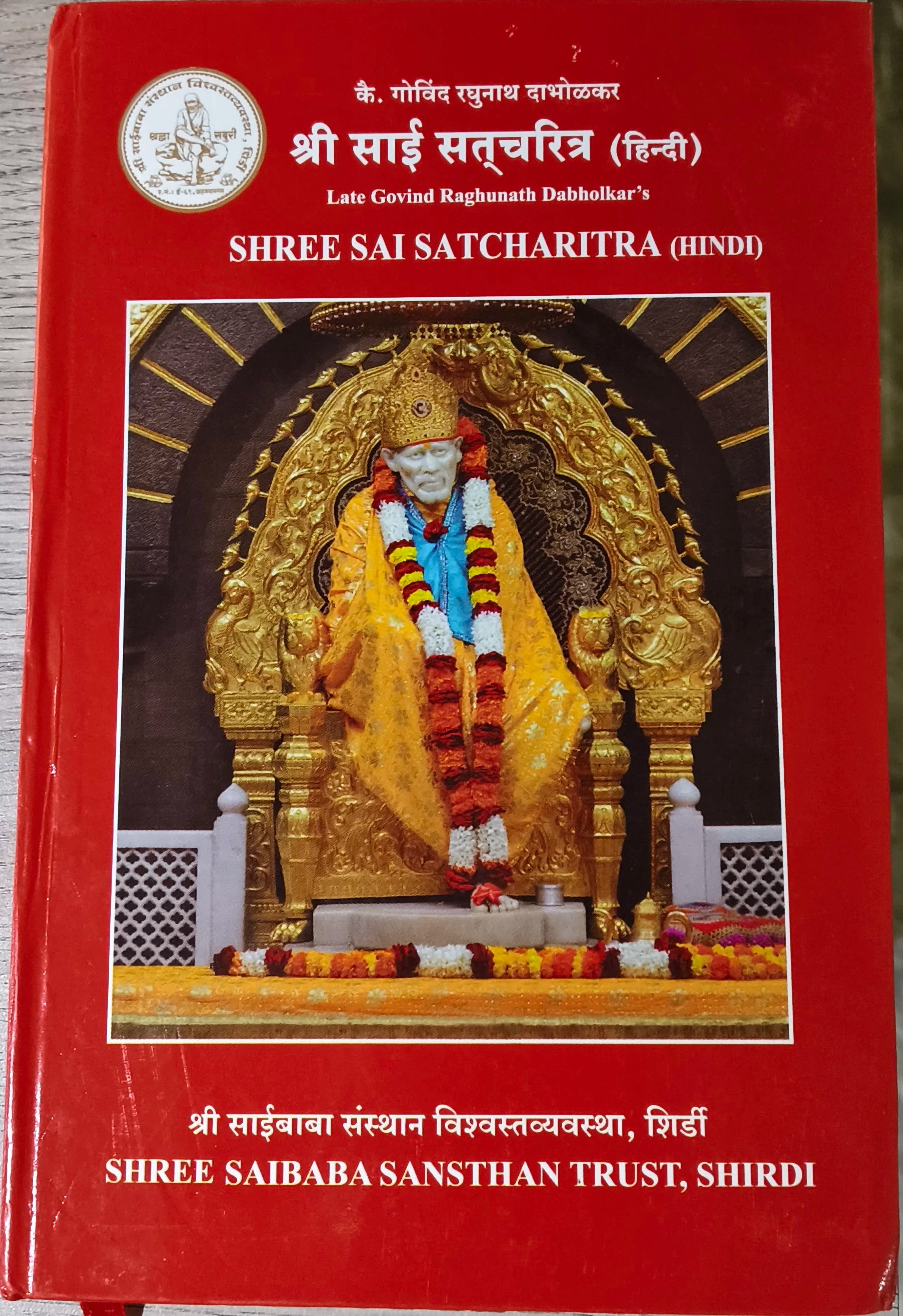 Red cover of Shree Sai Satcharitra book with Sai Baba statue and golden ornate background
